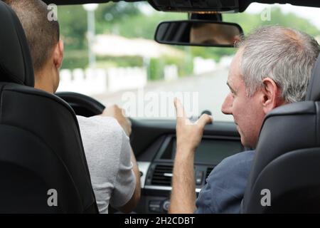 Rückansicht des Fahrlehrers mit dem Lernenden im Fahrzeug Stockfoto