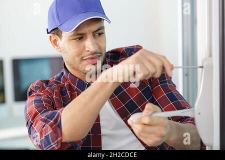 Ein junger Handwerker repariert Fenster Stockfoto