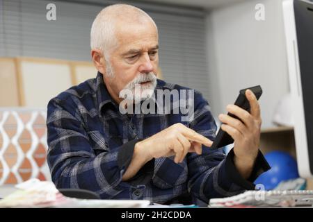 Leitender Geschäftsmann, der im Büro Rechner verwendet Stockfoto