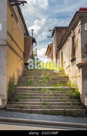 Schmutzige, nicht gepflegte Seitenstraße mit grasbedeckten Treppen zwischen den Gebäuden Stockfoto