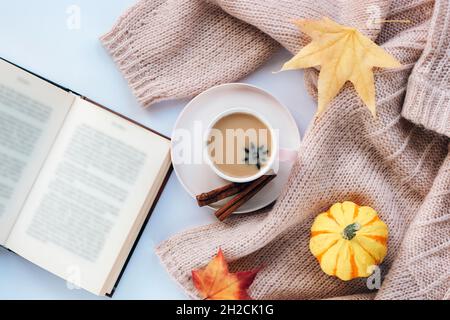 Heißer Kaffee mit Sternanise und Zimt in einer Tasse, einem offenen Buch, einem gelben Kürbis und Herbstblättern. Draufsicht, flach liegend. Herbstkonzept. Stockfoto