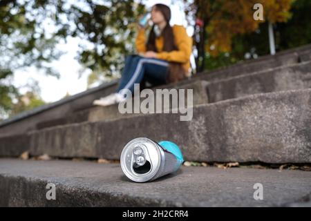 Eine gequetschte Aluminiumbüste und ein Teenager, der auf der Treppe Energie trinkt. Stockfoto