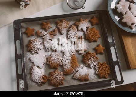 Verschiedene Weihnachts-Lebkuchen auf Backblech, mit Puderzucker Stockfoto