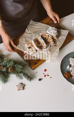 Baker serviert Weihnachtsgebäck, Stollen auf Holzbrett. Stockfoto