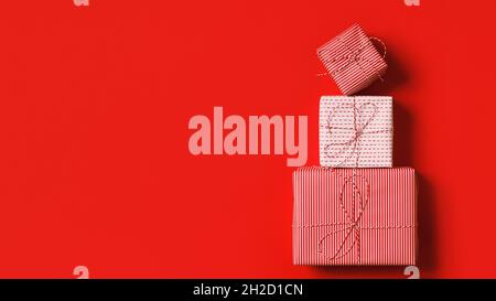 Stapel von Weihnachts-Geschenkschachteln für Neujahr auf rotem Hintergrund. Flach, oben liegend, Kopieplatz Stockfoto