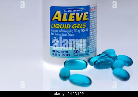 Flasche mit Aleve Flüssiggel-Tabs, Naproxen-Natriumkapseln mit vor auf weißem Hintergrund gestreuten Pillen, ein Bayer-Schmerzmittel, ein Fieberreduzierer Stockfoto