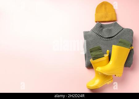 Pullover, Strickmütze und Stiefel auf rosa Hintergrund. Stockfoto