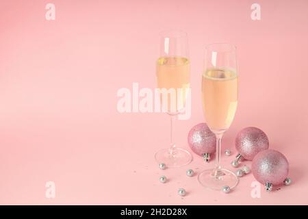 Gläser Champagner und Kugeln auf rosa Hintergrund. Stockfoto