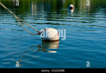 Festmachen Ball Verankerung Linien von einem unsichtbaren Boot. Wasser ist ein lebhaftes Blau mit interessanten Oberflächenmustern. Speicherplatz kopieren. Hintergrund. Stockfoto