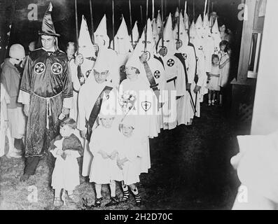 Vintage-Foto um 1924 mit Mitgliedern des Ku Klux Klan, die mit kleinen Kindern in Kleidern und Kapuzen von klan an an einer Hochzeit teilnehmen Stockfoto