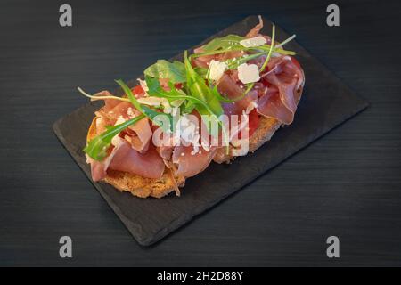 Sandwich mit Schinken, Käse, Tomaten und Salat. Auf der Steinplatte. Nahaufnahme Stockfoto