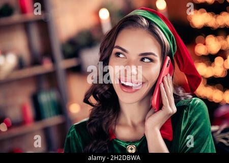 Foto von verträumt charmante junge Dame tragen elf Kleidung feiert weihnachten Gespräch modernes Gerät lächelnd im Haus Hauszimmer Stockfoto