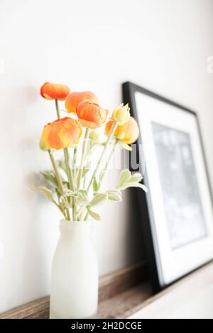 Vase mit Ranunculus auf einem Regal in einem hellen, luftigen Raum Stockfoto