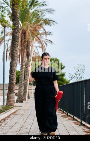 Junge Frau, die nach dem Kung-Fu-Training mit einem Stock im Park spaziert hat Stockfoto