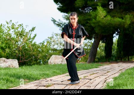 Frau übt Kung Fu mit einem Stock Stockfoto