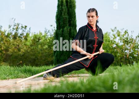 Frau übt Kung Fu mit einem Stock Stockfoto