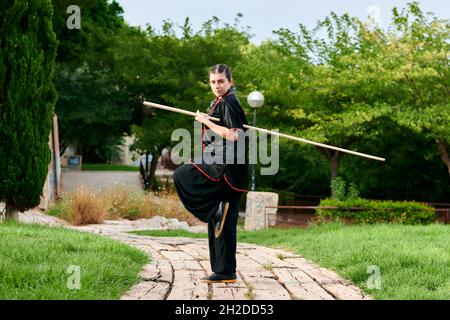 Frau übt Kung Fu mit einem Stock Stockfoto