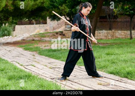 Frau übt Kung Fu mit einem Stock Stockfoto