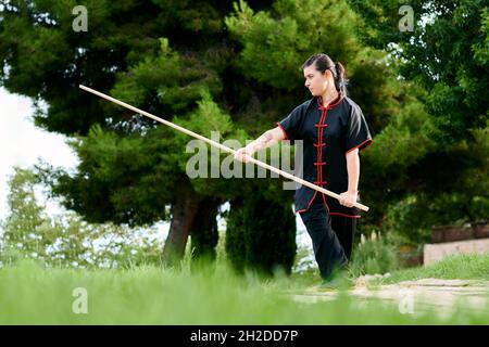 Frau übt Kung Fu mit einem Stock Stockfoto