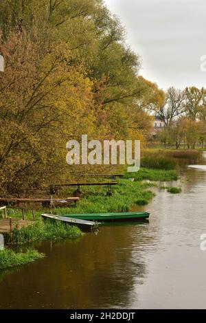 Herbstbäume am Fluss und Boote vor dem Pier. Stockfoto