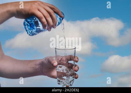 Person gießt Wasser im Glas mit weißem Hintergrund - gesunder Lebensstil Stockfoto