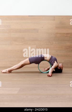 Junge flexible Frau tun, purvottanasana yoga Pose mit Rad Stockfoto