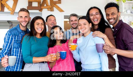 Junge, multiethnische Gruppe von Freunden feiert Frühstück und Kaffee in einer Sky Bar des Hotels und macht sich im Urlaub im Restaurant drinnen lustig Stockfoto