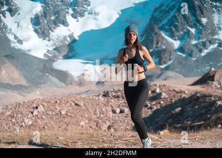 Mädchen läuft auf dem Trail in den verschneiten Bergen. Stockfoto