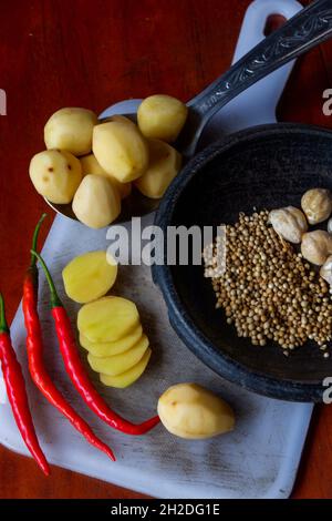 Blick von oben auf frische rohe Kartoffeln und rote Chilischoten auf einem Holztisch Stockfoto