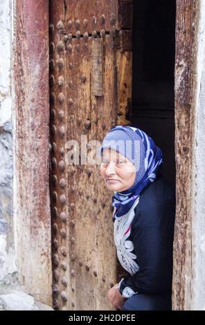 Fez, Marokko - 23. Februar 2019: Eine ältere Frau aus Berber-Ethnie in traditioneller Kleidung in ihrem Haus in einer engen Seitenstraße der Medina, Fez, Marokko. Stockfoto