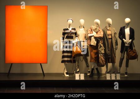 Weibliche Schaufensterpuppen in der Nähe von rotem Stand. Stehende Dummies im Frühling Herbst oder Winter Kleidung. Stockfoto