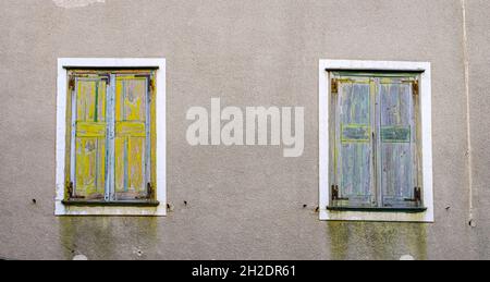 Zwei alte Fenster auf grauer Wand. Geometrie und Architektur. Stockfoto
