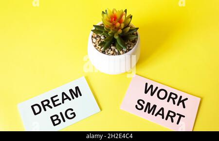 Motivations-Zitat TRAUM GROSS und ARBEIT SMART auf Sticker und gelben Hintergrund geschrieben Stockfoto