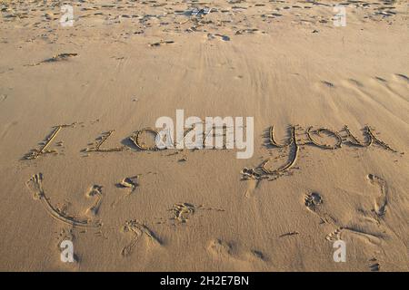 Words I Love You Schreiben auf dem Sand am Strand vor Hintergrund. Liebesbriefe auf dem Sand. Stockfoto