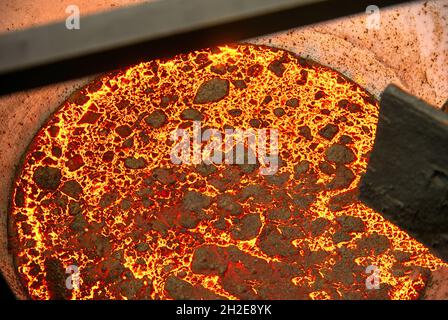 Die Oberfläche einer heißen flüssigen Schlacke in einer metallurgischen Pfanne. Dicke Kruste mit Müllnetz bedeckt Stockfoto