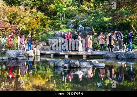 Holland Park, London, Großbritannien. Oktober 2021. Die Menschen bewundern das Wasserspiel im Kyoto Garden im Holland Park, einem japanischen Garten, der japanische Landschaftsgestaltung nach London bringen soll. Die Bäume des Gartens beginnen, ihre schönen Herbstfarben in der heutigen schönen Sonne zu zeigen. Kredit: Imageplotter/Alamy Live Nachrichten Stockfoto