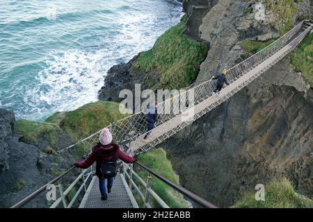 Touristen überqueren die Carrick-a-rede-Seilbrücke, eine beliebte Touristenattraktion in Nordirland. Ballintoy, County Antrim, Nordirland 18.11.2019 Stockfoto