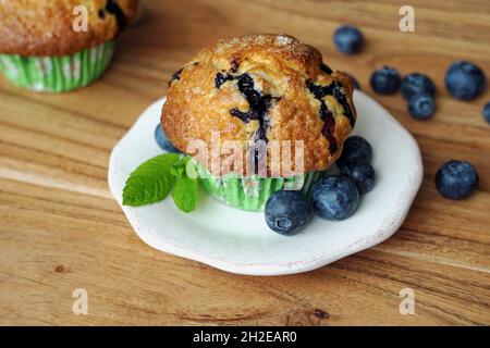 Hausgemachter Blaubeer-Muffin auf Beilagenteller, garniert mit Heidelbeeren und frischem Minzblatt Stockfoto