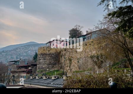 Bursa an bewölkten und regnerischen Tagen. Foto vom Bezirk tophane durch den ulu-Berg (uludag) im Hintergrund und mit pinkfarbenem Café und Restaurant Stockfoto