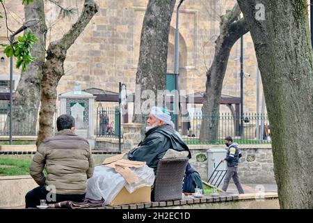 Ein alter Mann in islamischer traditioneller Kleidung und Turban in der Nähe der großen Moschee (ulu camii) in Bursa während regnerischer Tage und bewölktem Himmel. Stockfoto