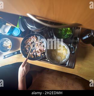 Spaghetti, die in kochendem Wasser gekocht werden, zusammen mit Walnuss, Schinken und Knoblauch, die in einem Topf gebraten werden. Italienisches Gericht, Pasta. Kochen oder Stockfoto