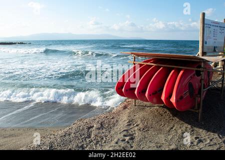 Agia Marina Resort, Kreta, Griechenland wunderschöne Seeszene mit Wellen und Wellenbrechern auf den Strandkajaks, die in einer Reihe im Vordergrund Landscap gestapelt sind Stockfoto