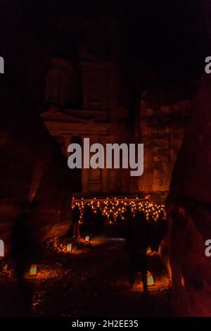 CANDELS entlang der engen Siq Schlucht, Haupteingang zur antiken Stadt Petra während Petra bei Nacht, Jordanien. Al Khazneh Tempel das Schatzamt im Hintergrund Stockfoto