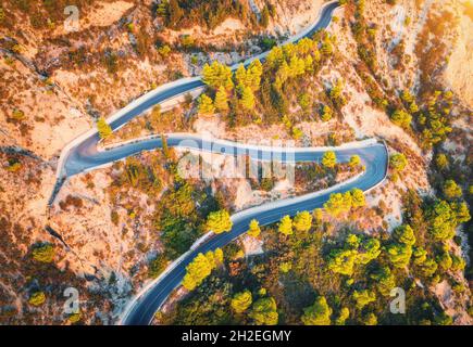 Luftaufnahme einer kurvenreichen Straße in den wunderschönen Bergen bei Sonnenuntergang Stockfoto
