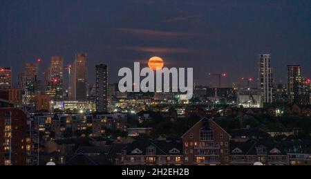 London, Großbritannien. Oktober 2021. Mondaufgang über Ost-London. 98.8 % schwindender, krümeliger Mond steigt über der Skyline der Stadt am frühen Abend während eines zunehmend warmen Oktober auf. Kredit: Guy Corbishley/Alamy Live Nachrichten Stockfoto