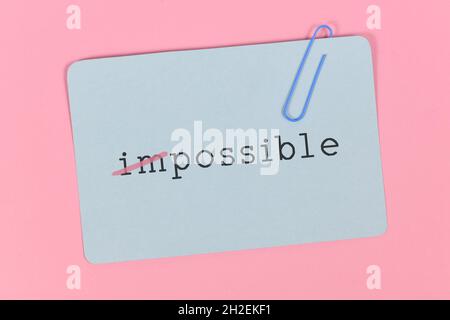 Wort unmöglich in Wort möglich auf blauer Karte auf rosa Hintergrund geändert Stockfoto