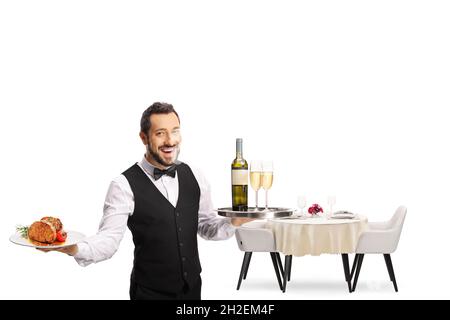 Der Kellner hält einen Teller mit Steak und ein Tablett mit Wein und einen Restauranttisch dahinter isoliert auf weißem Hintergrund Stockfoto