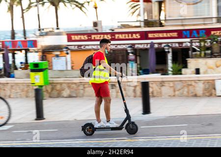 Junger Mann mit Geschwindigkeit fährt auf einem Elektroroller in Can Pastilla in der Nähe von Palma Mallorca Spanien Stockfoto