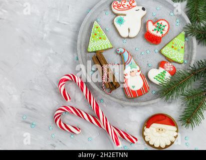Weihnachts-Lebkuchen auf einem grauen Tablett neben Tannenzweigen. Mockup mit Kopierbereich. Neujahrskarte, Dekorationen. Nahaufnahme Stockfoto