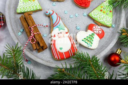 Weihnachts-Lebkuchen auf einem grauen Tablett neben Tannenzweigen. Mockup mit Kopierbereich. Neujahrskarte, Dekorationen. Nahaufnahme Stockfoto